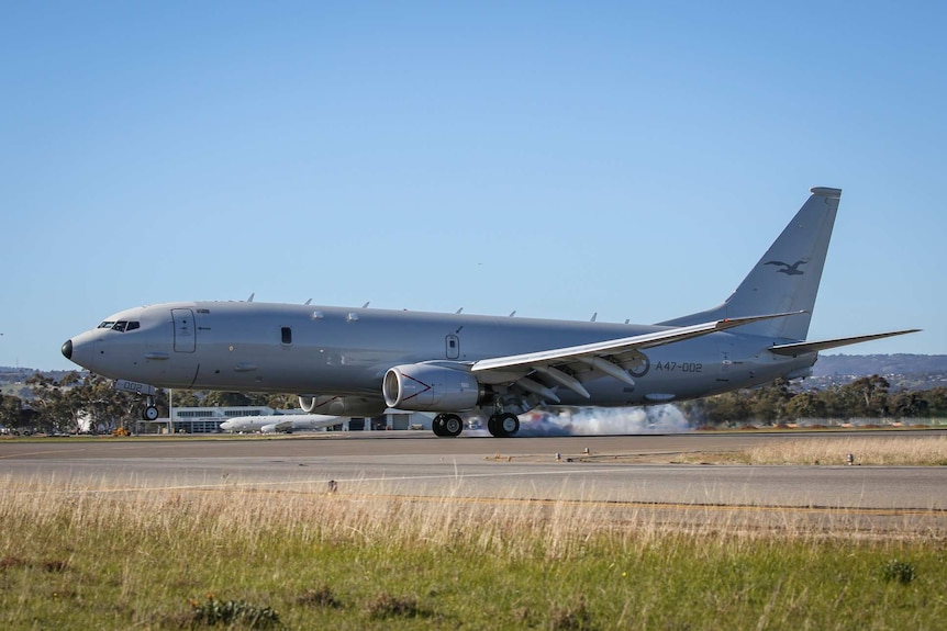 A grey plane sits on an airport runway