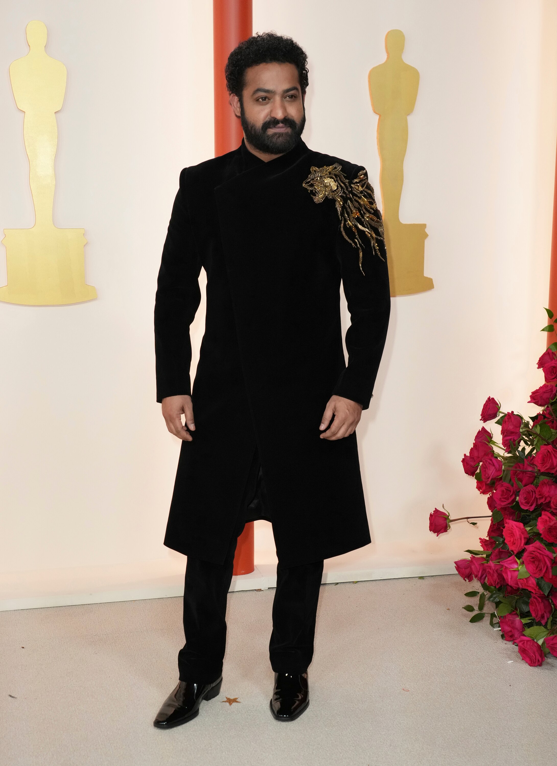 N T Rama Rao Jr wearing an all-black suit with a gold tiger embellishment on one shoulder