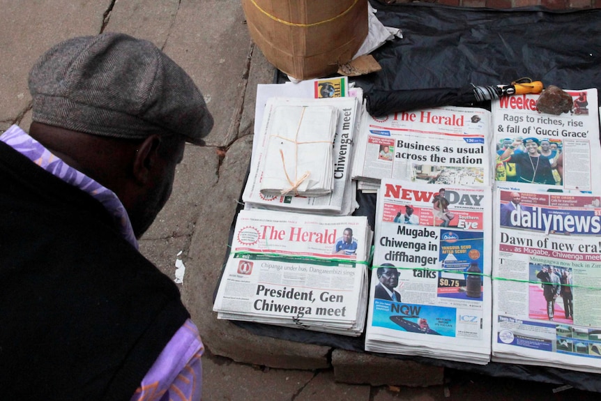 A man reads the headlines of newspapers for sale on a street in Harare, Zimbabwe.
