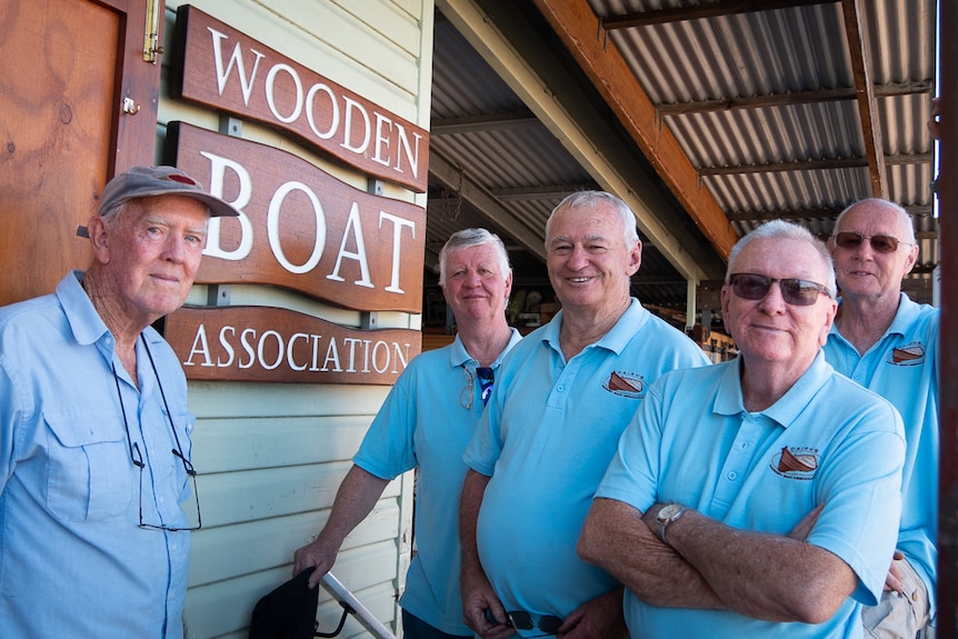 Some of the members of the Wooden Boat Association standing in front of their club sign