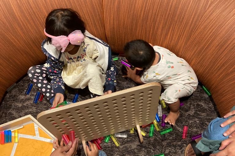 A photo of Raidah's children playing with toys, shot from an above angle so faces are not showing.