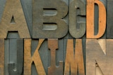 Wooden type blocks in alphabetical order over three rows.
