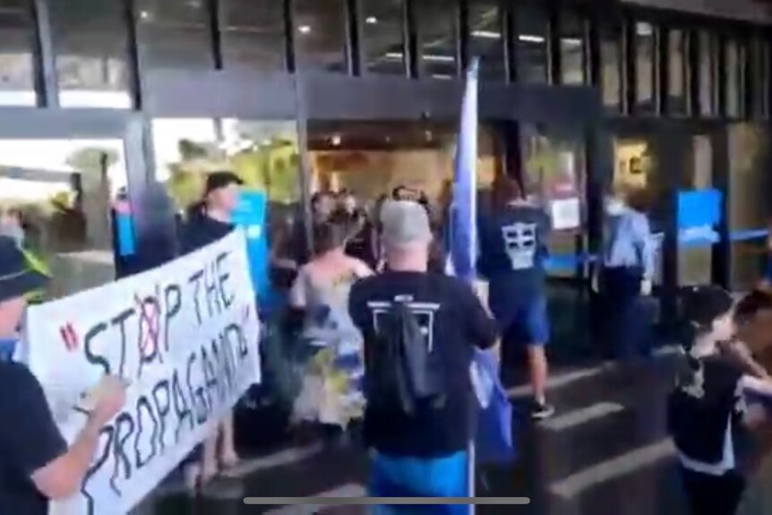 A group of people are blocked from entering a shopping centre by police 