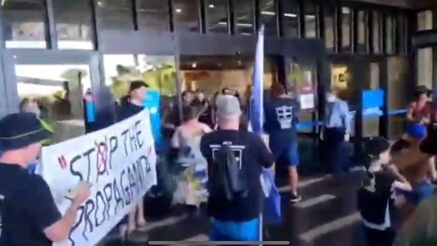 A group of people are blocked from entering a shopping centre by police.
