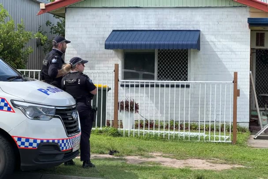 Queensland police officers stand outside North Mackay house linked to death of child the night earlier