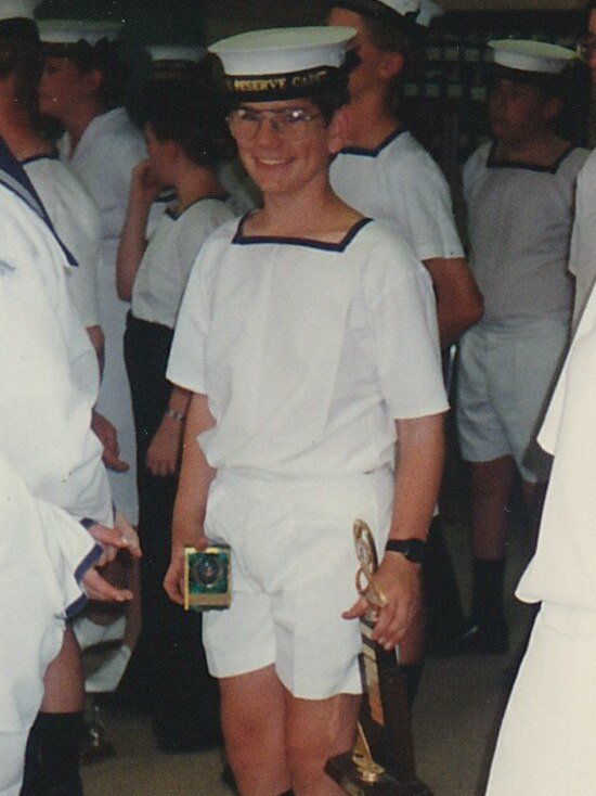 Boy wearing cadet uniform holding trophies.