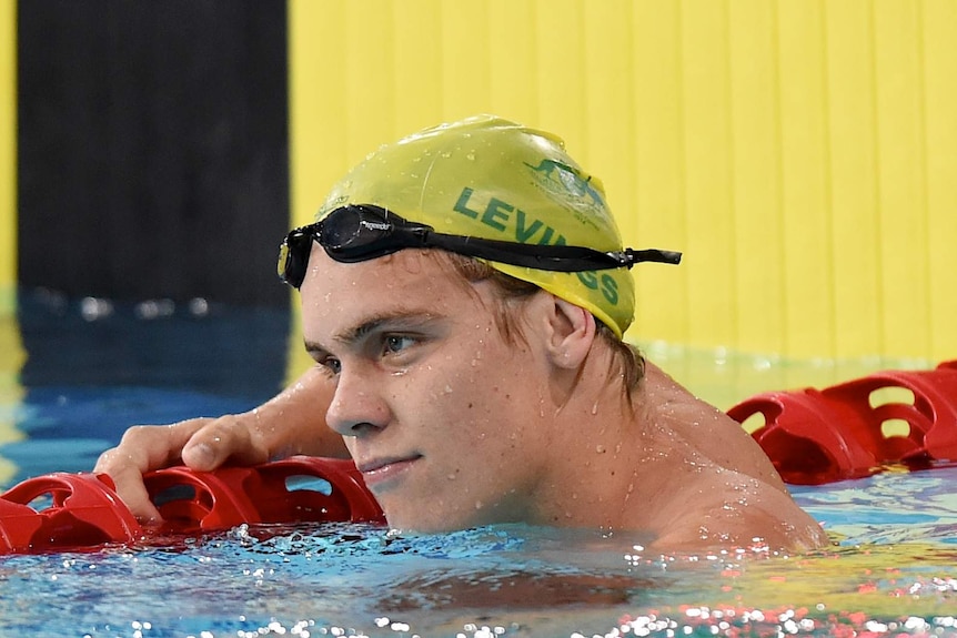 Matthew Levings looks on while resting on a lane rope during swimming heats in Glasgow