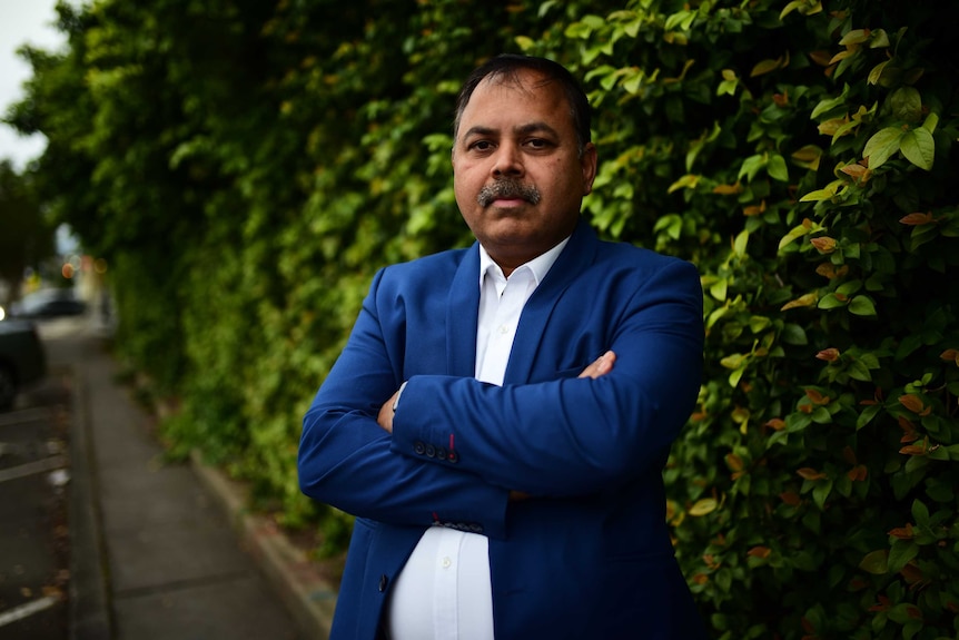 A business man in front of a tall hedge