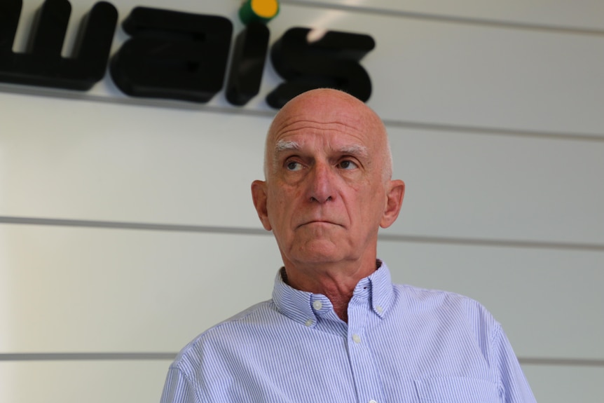 Neil McLean wearing a blue business shirt, with the WAIS logo on a wall behind him.