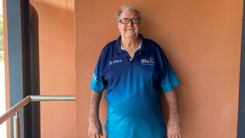 A man in blue Broome Sports Association polo shirt stands in front of an orange wall