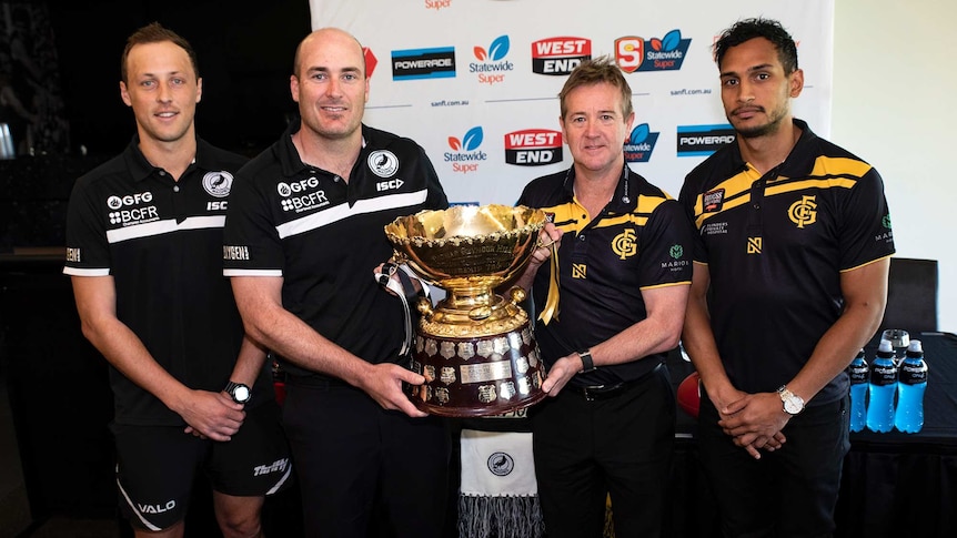 Four men hold an SANFL premiership cup