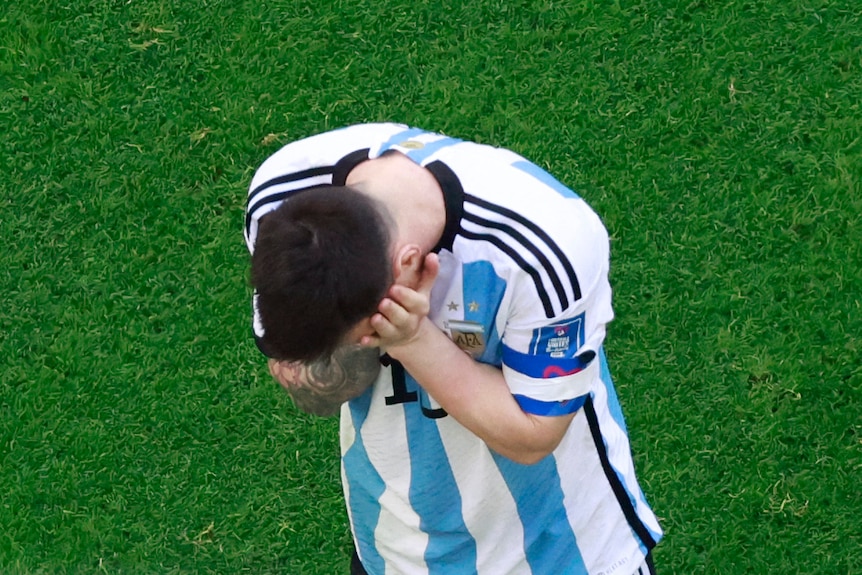 A football player covering face with hands.
