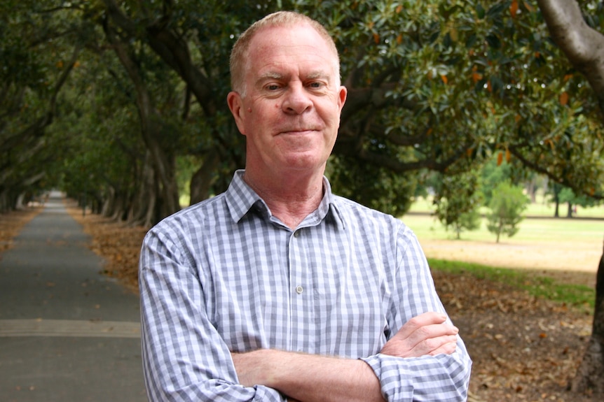 A man standing in princess park, Melbourne, Australia, smiling to the camera.  