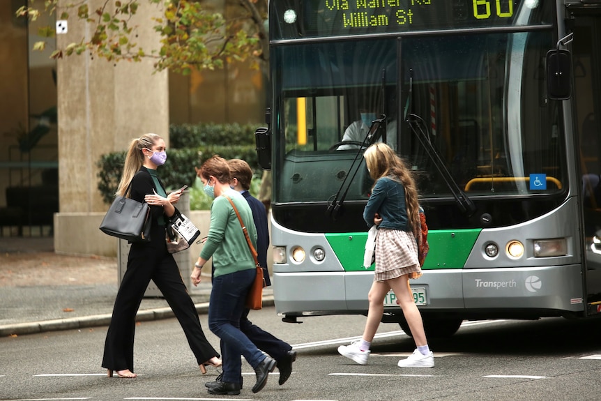 People wearing masks and crossing a road in Perth's CBD.