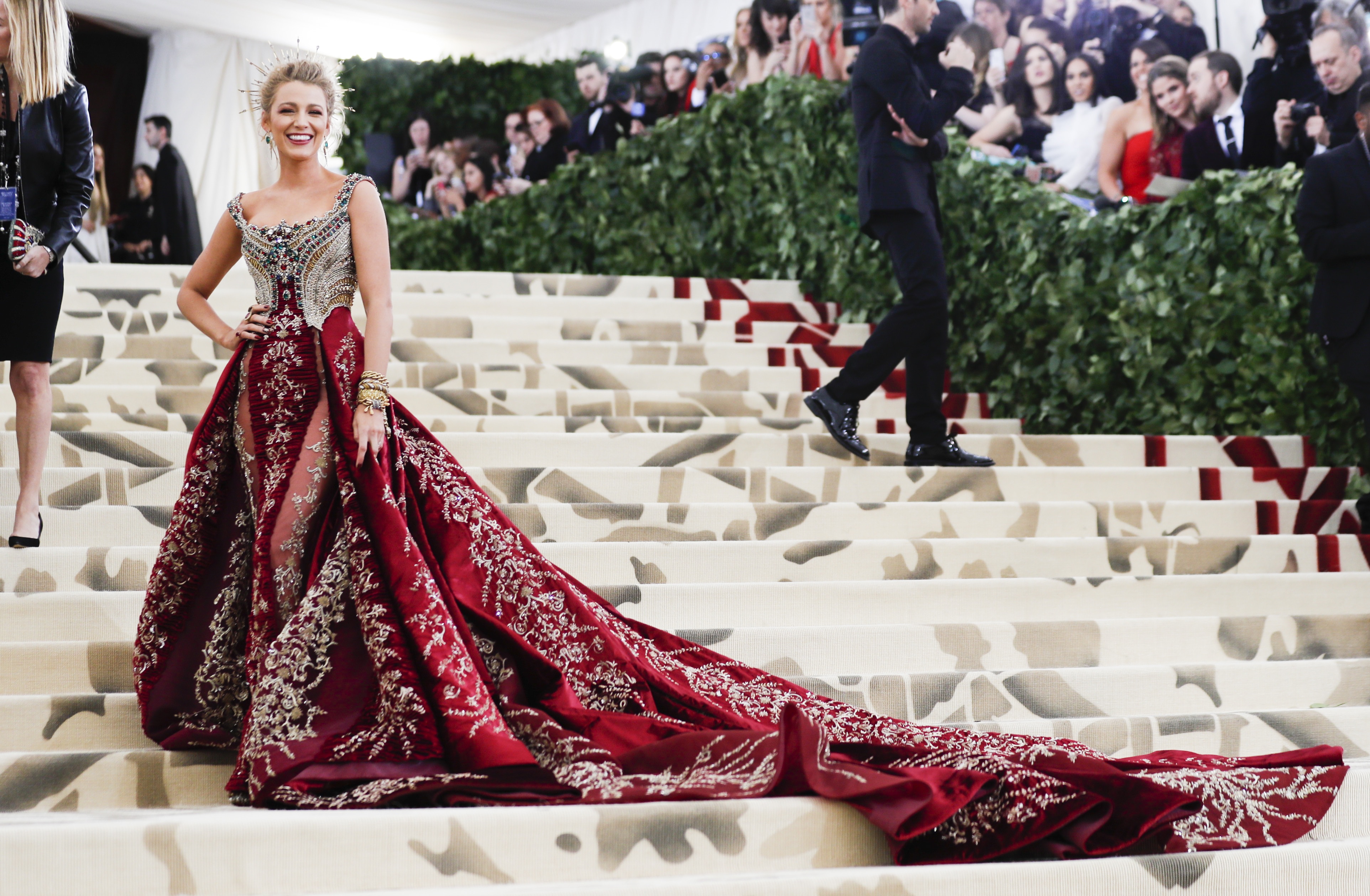 Blake Lively wearing a gown with an embellished gold metallic top and a red velvet skirt with a halo-like crown