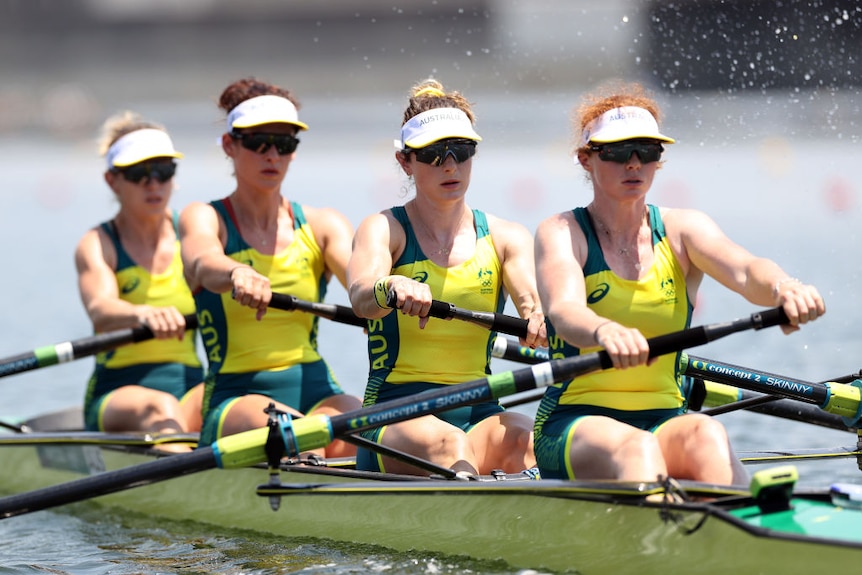 Four female Australian rowers in action, they all look like they are concentrating and are wearing matching uniforms