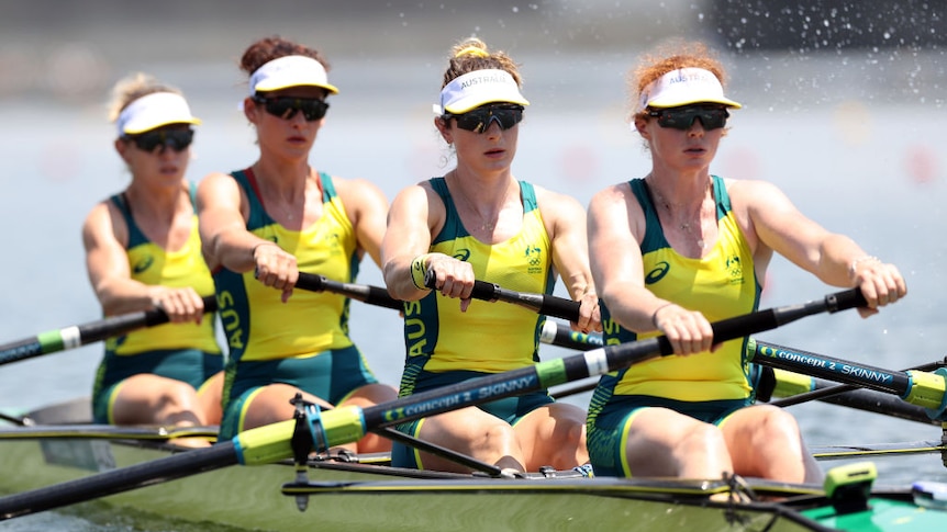 Four female Australian rowers in action, they all look like they are concentrating and are wearing matching uniforms