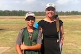 Senator Bridget McKenzie holds a gun and smiles while standing next to a young boy also holding a gun