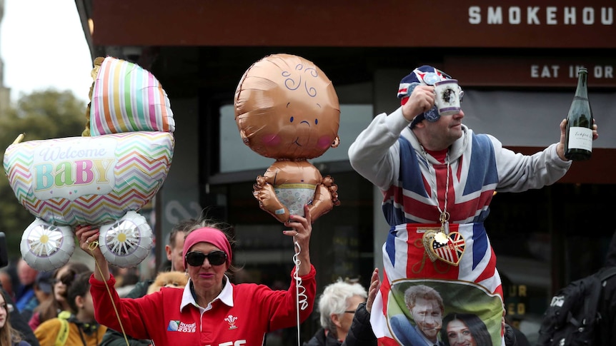 Royal fans carry balloons and champagne to celebrate in front of Windsor Castle.