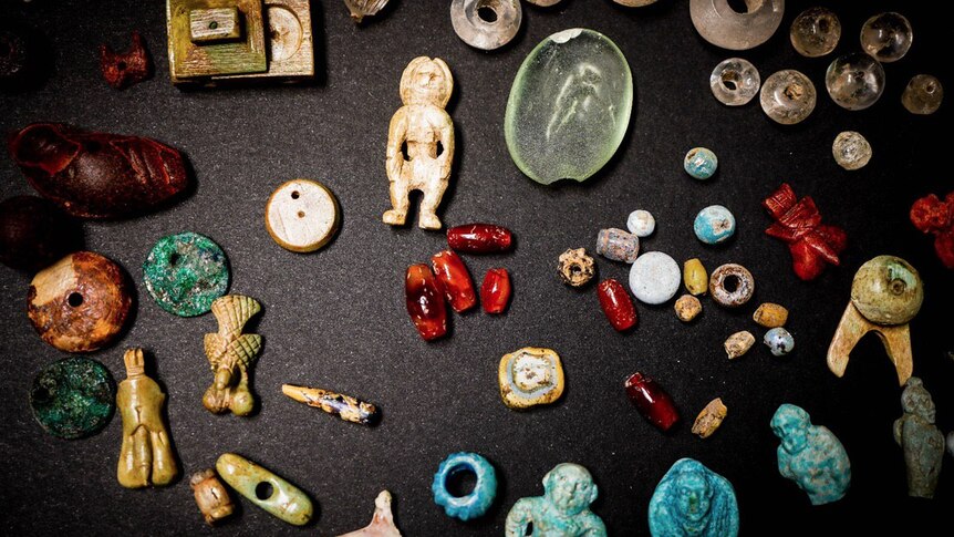 Various good luck charms and parts of a necklace spread on a carpet.