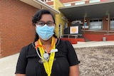 A young female doctor standing outside a hospital emergency department