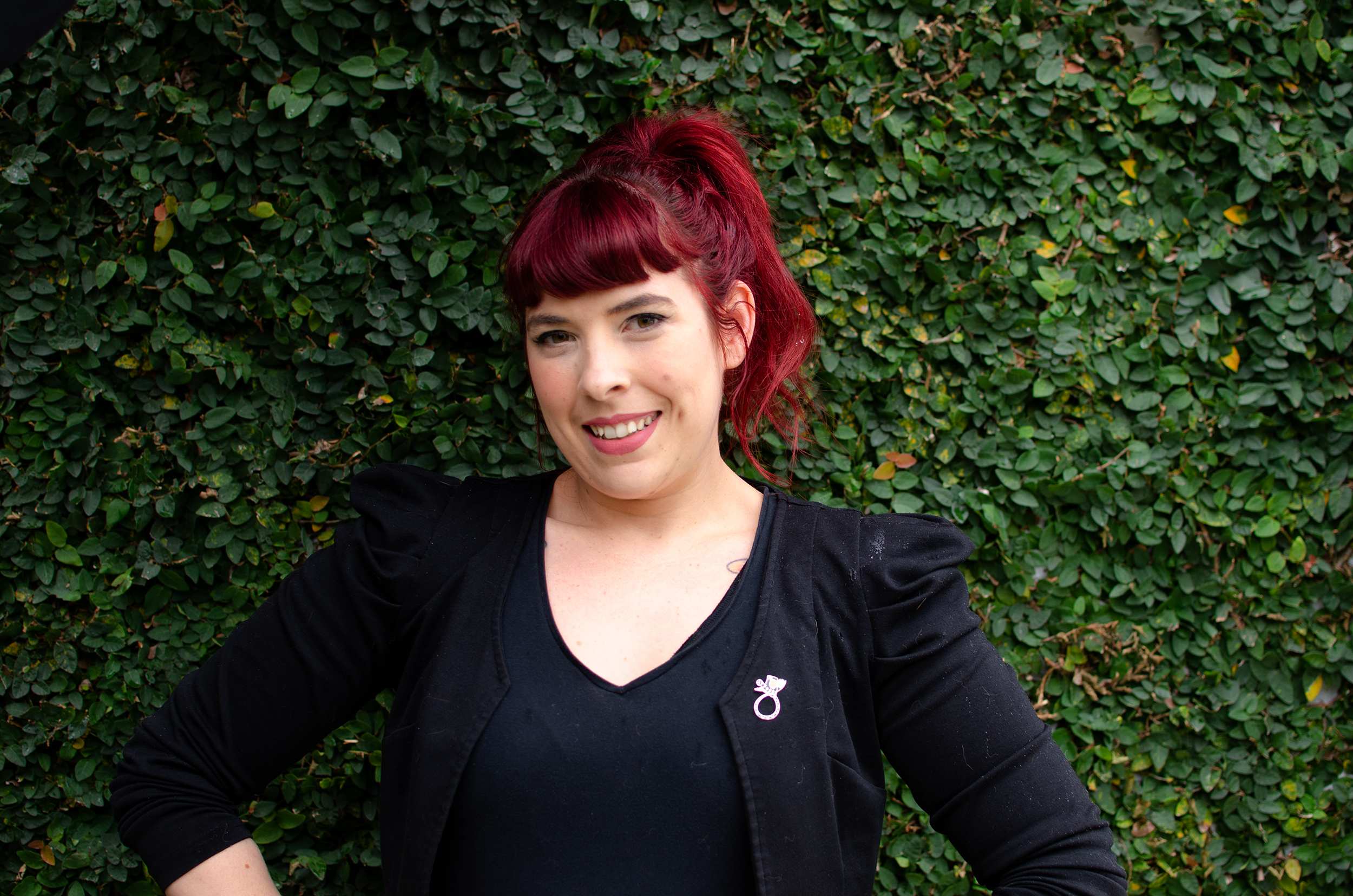 Jess Hill poses for a headshot in front of a hedge for a story about sterilisation when you're young and don't want kids.