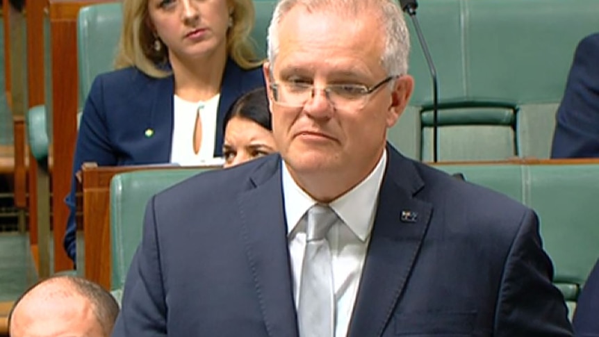 Prime Minister Scott Morrison in Parliament wearing a dark blue suit and a light blue tie.