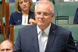 Prime Minister Scott Morrison in Parliament wearing a dark blue suit and a light blue tie.