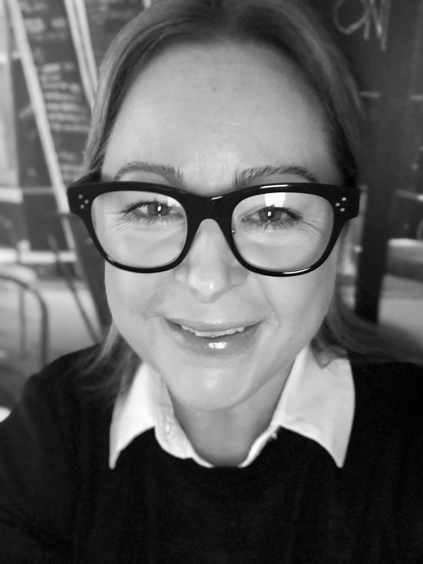 A black and white close up of Erin wearing glasses.