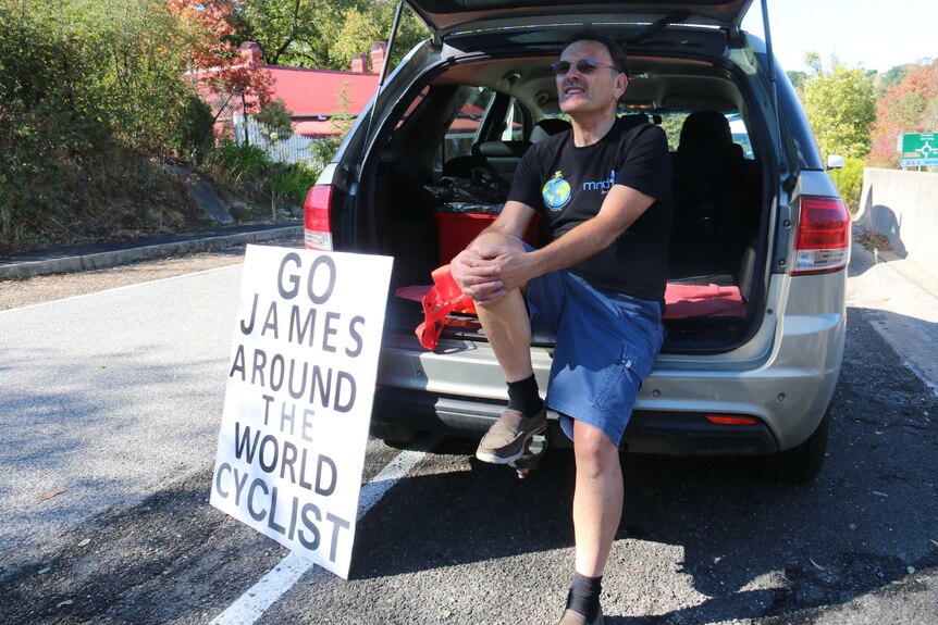Family friend Mike Ainsworth sits in the back of his car with a support sign for Jimmy Ashby.