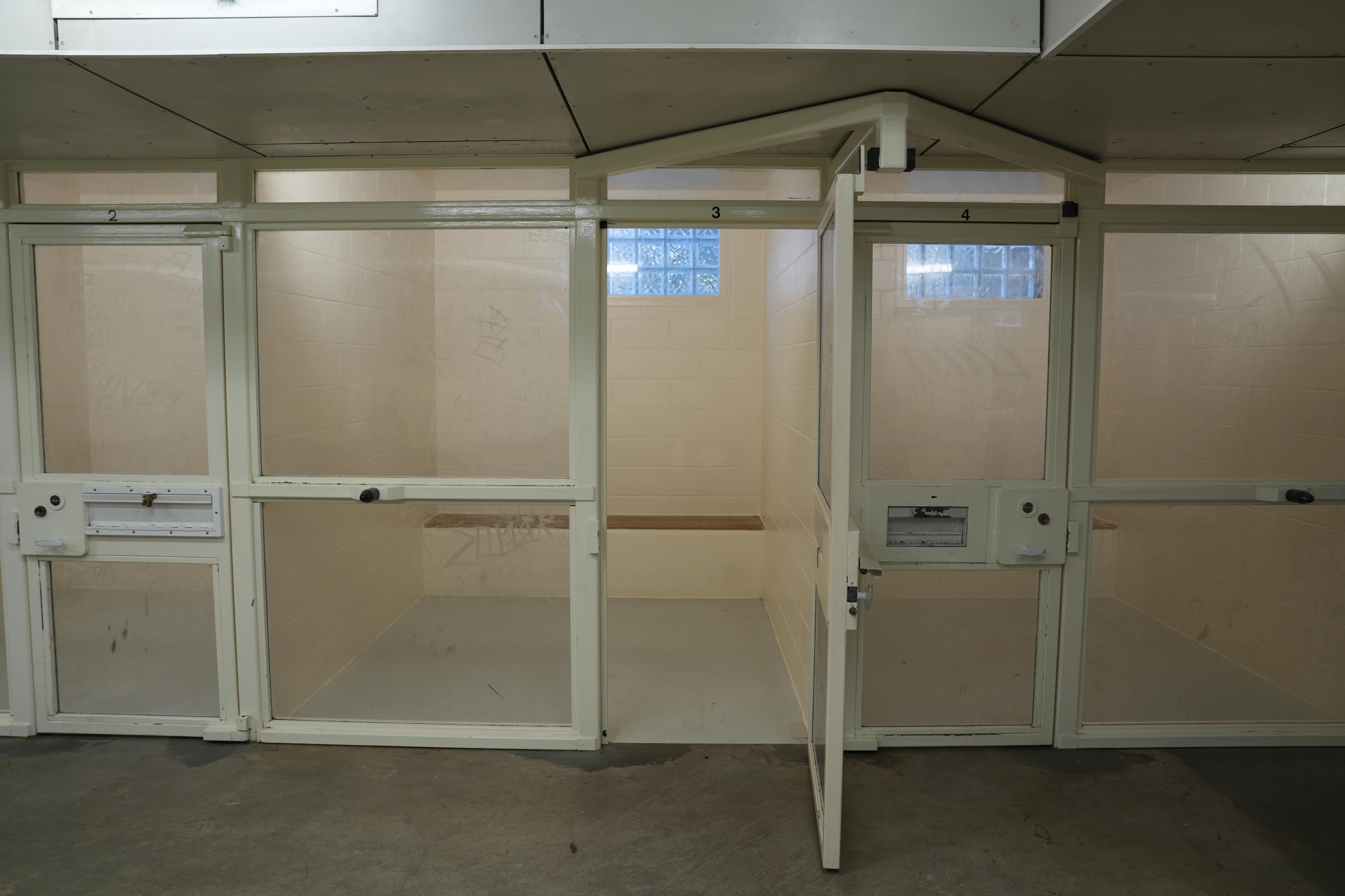 Tres pequeñas celdas una al lado de la otra con paredes de plexiglás. se abre una puerta