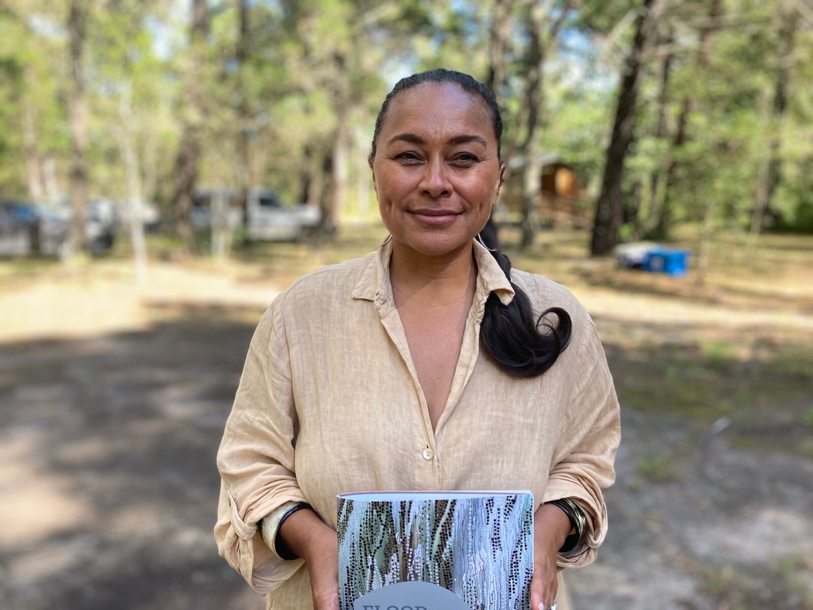 Woman in beige dress holds a report.