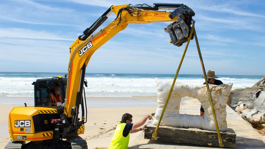 A crane moves one of the Sculpture by the Sea artworks after tidal damage.