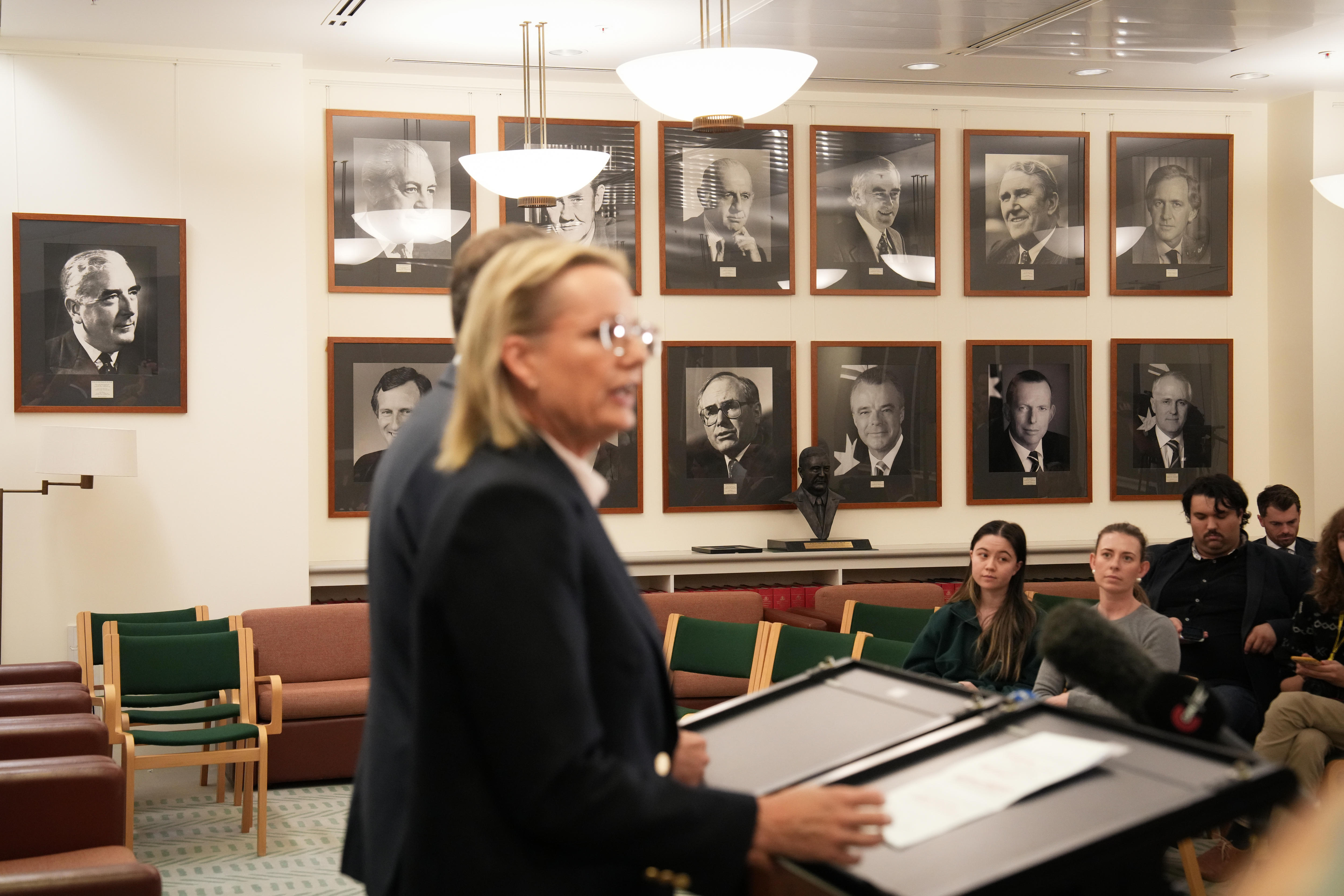 Sussan Ley talks at a lecturn, behind her are the photographs of former Liberal prime ministers