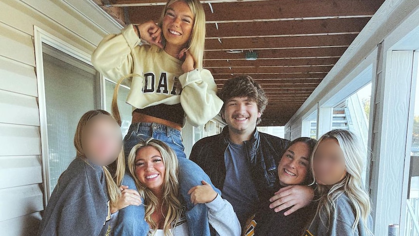 Five young women and a man stand together for a photo on a porch