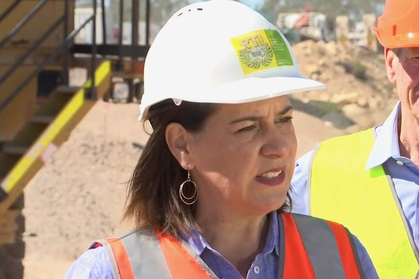 A woman in a hardhat talking to reporters