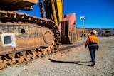 Woman inspecting mining machinery in an open pit mine.