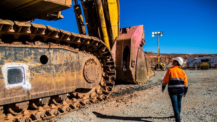 Woman inspecting mining machinery in an open pit mine.