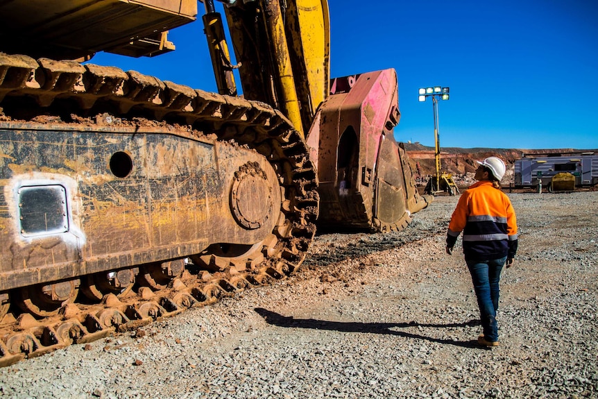 Woman inspecting mining machinery in an open pit mine.