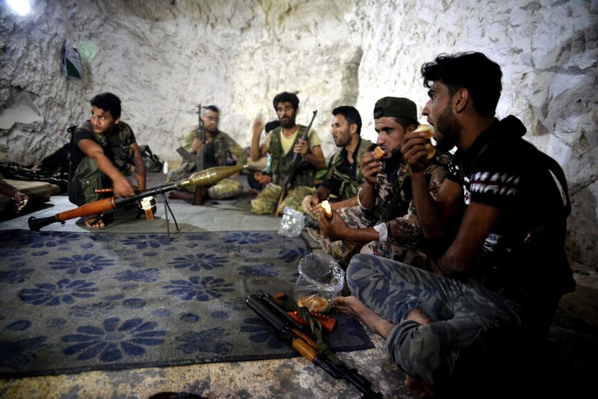 Fighters with the Free Syrian army eat in a cave where they live
