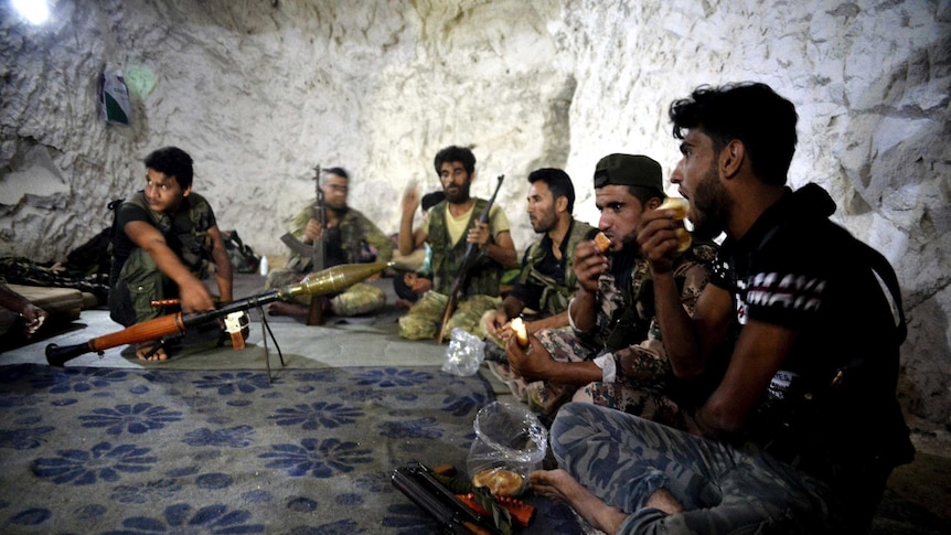 Fighters with the Free Syrian army eat in a cave where they live