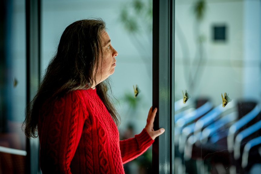 Fiona McKenzie stands in front of a full length window and looks outside.