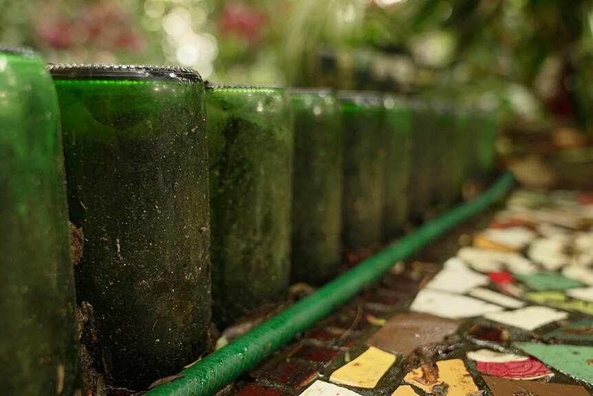 Green glass bottles against a mosaic floor.