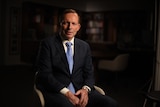 Tony Abbott sits in a chair with his hands in his lap.