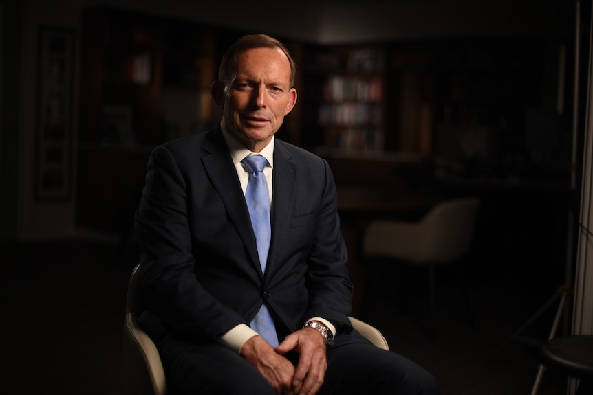 Tony Abbott sits in a chair with his hands in his lap.