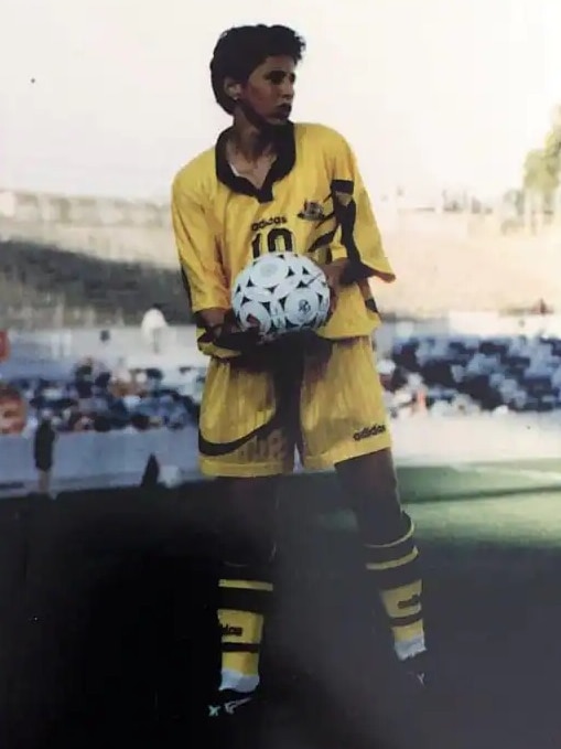 A soccer player wearing yellow holds a ball in her hands during a game