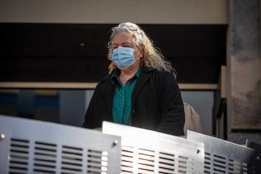 A woman wearing a face mask walks down the stairs in front of the Magistrates Court in Hobart. 