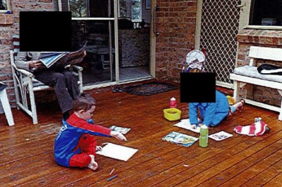 Two children play with crayons on a deck