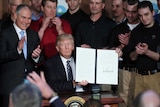 Donald Trump holds up the signed executive order.
