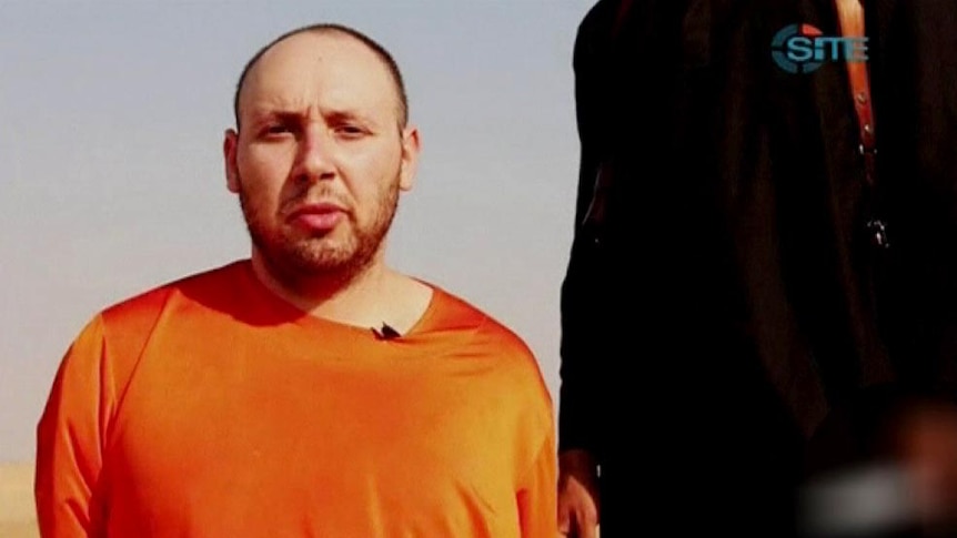 An Islamic State militant stands next to captured American journalist Steven Sotloff.